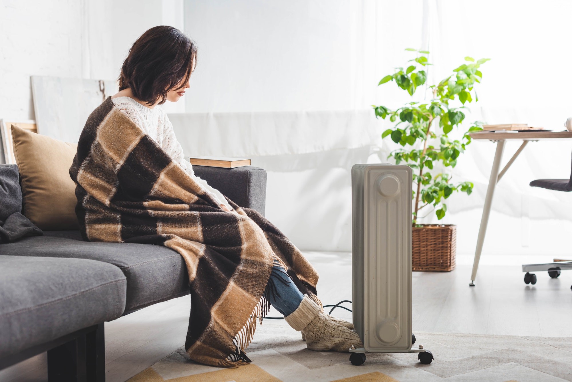 beautiful woman with blanket in cold room with heater